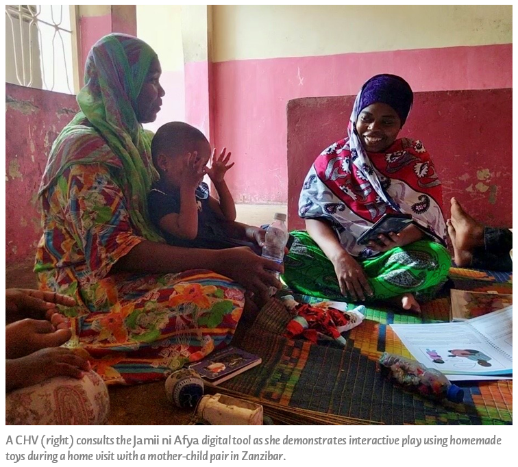 A CHV (right) consults the Jamii ni Afya digital tool as she demonstrates interactive play using homemade toys during a home visit with a mother-child pair in Zanzibar.